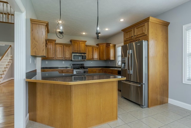 kitchen with light tile patterned floors, appliances with stainless steel finishes, a healthy amount of sunlight, and pendant lighting