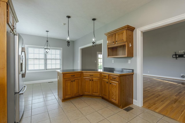 kitchen featuring stainless steel refrigerator with ice dispenser, decorative light fixtures, light tile patterned floors, and kitchen peninsula