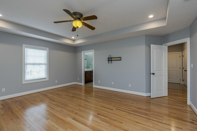 spare room featuring light hardwood / wood-style floors, a raised ceiling, and ceiling fan