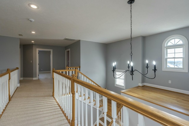 hall with light carpet and a notable chandelier