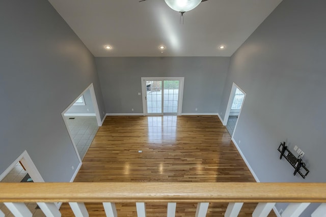 unfurnished living room with ceiling fan, a high ceiling, and hardwood / wood-style floors