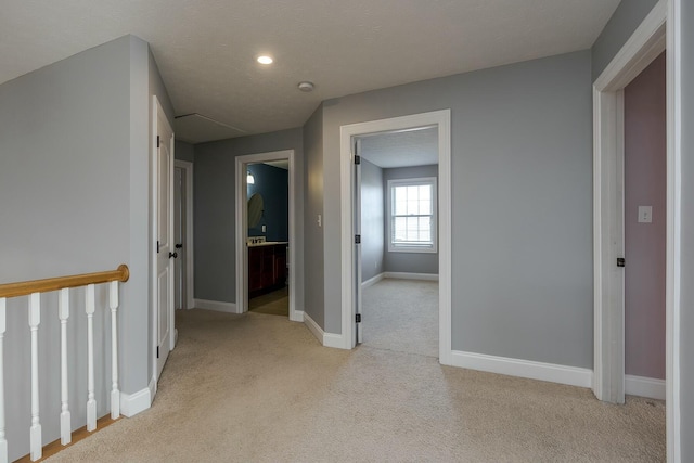 hallway with light carpet and a textured ceiling