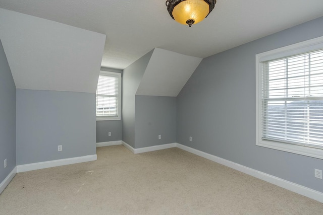 additional living space featuring light colored carpet and vaulted ceiling