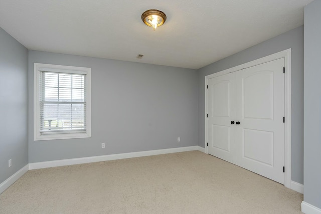 unfurnished bedroom with light carpet and a closet