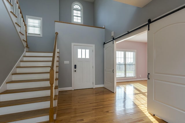 foyer entrance with a barn door, a high ceiling, and light hardwood / wood-style flooring