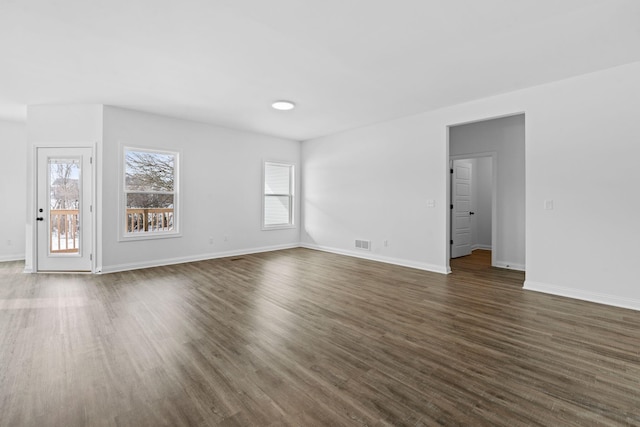 unfurnished living room featuring baseboards, visible vents, and dark wood-style flooring