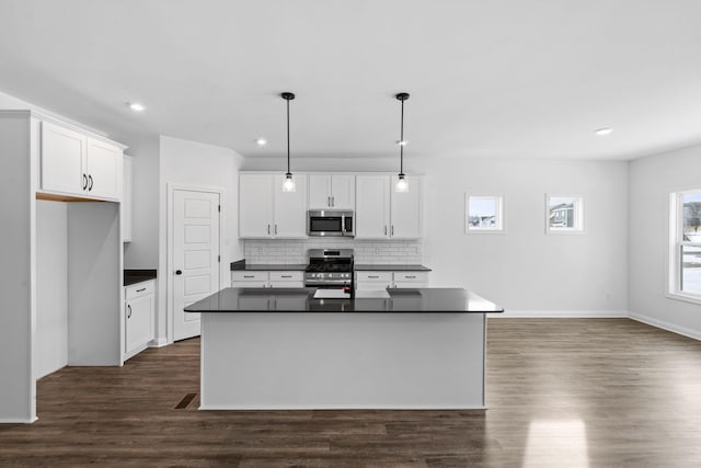 kitchen featuring stainless steel appliances, dark countertops, decorative backsplash, dark wood-type flooring, and white cabinetry