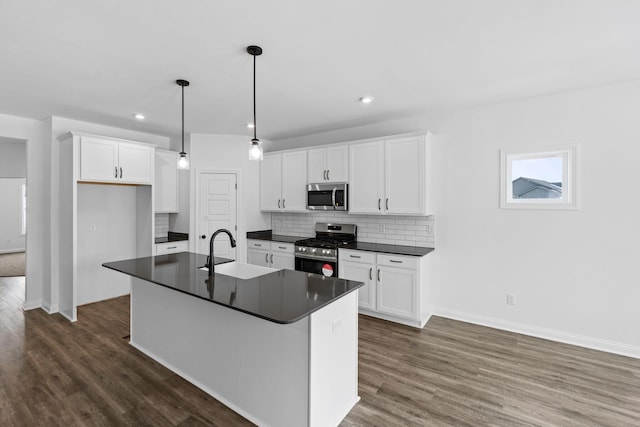 kitchen with stainless steel appliances, dark countertops, backsplash, and white cabinetry