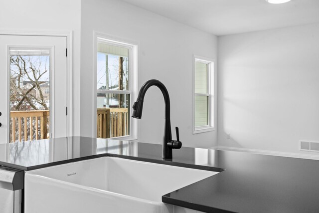 details featuring dishwasher, dark countertops, a sink, and visible vents