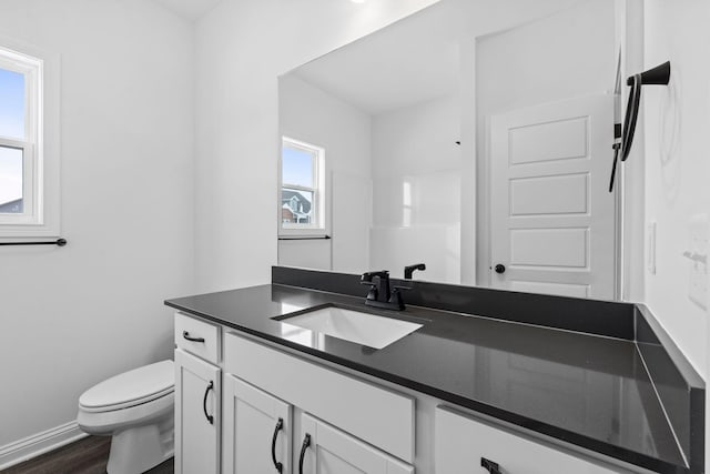 bathroom with baseboards, vanity, toilet, and wood finished floors