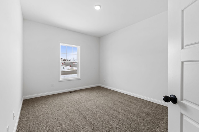 empty room with carpet floors, visible vents, and baseboards