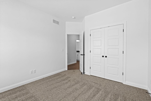 unfurnished bedroom featuring baseboards, a closet, visible vents, and carpet flooring