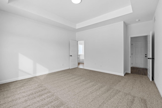 unfurnished bedroom featuring carpet, a raised ceiling, and baseboards