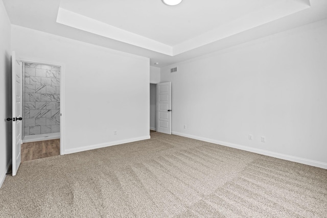 unfurnished bedroom with ensuite bathroom, visible vents, baseboards, carpet, and a raised ceiling