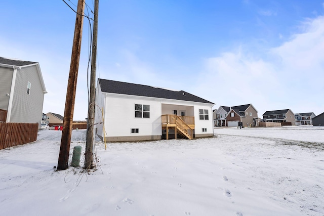 snow covered back of property featuring a wooden deck