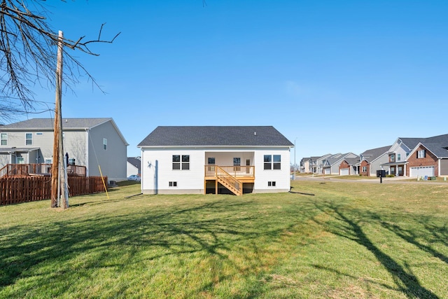 back of house featuring a residential view, a lawn, fence, and stairs