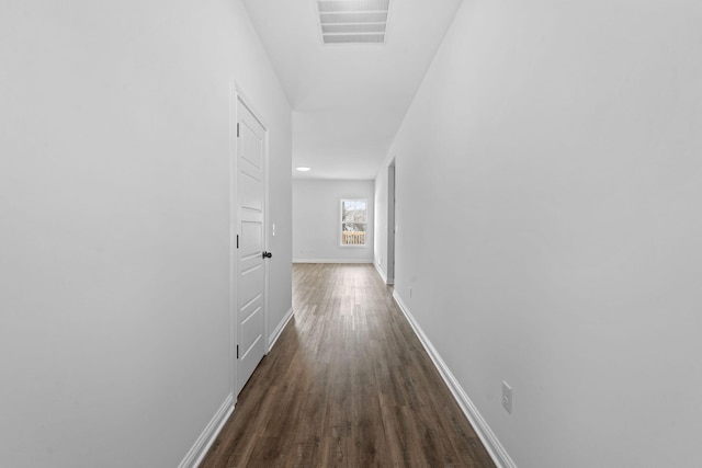 corridor featuring dark wood-style floors, visible vents, and baseboards