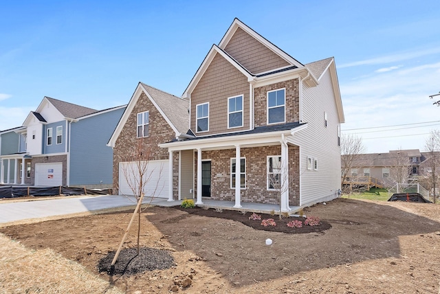 view of front of home featuring brick siding, covered porch, an attached garage, and concrete driveway