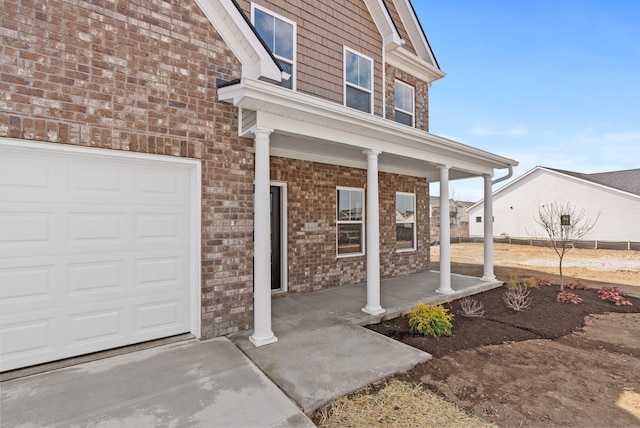 property entrance with brick siding, a porch, and a garage