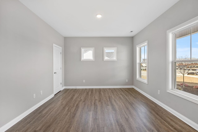 spare room with baseboards and dark wood-style flooring