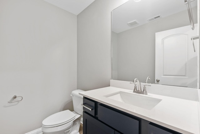 half bathroom featuring visible vents, toilet, vanity, and baseboards