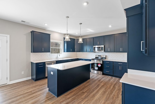 kitchen with a sink, stainless steel appliances, blue cabinetry, and a kitchen island