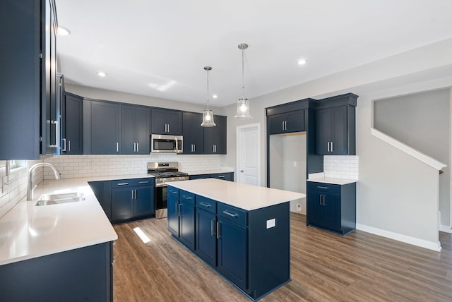 kitchen featuring blue cabinets, dark wood-type flooring, a sink, a kitchen island, and stainless steel appliances