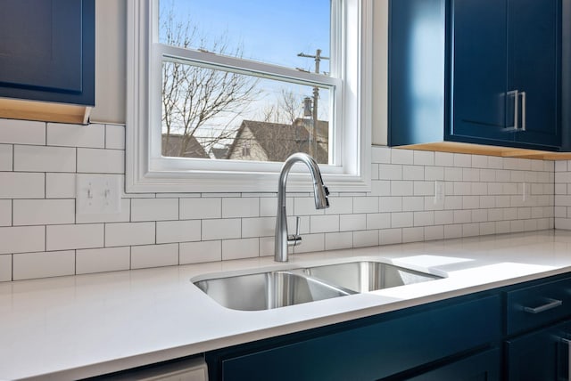 kitchen featuring blue cabinetry, light countertops, and a sink