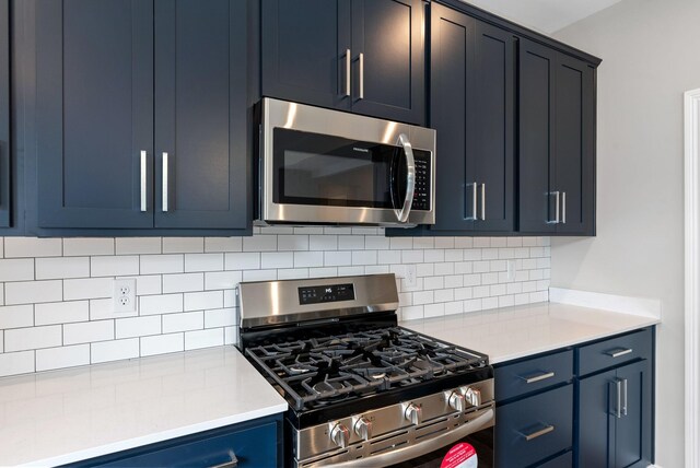 kitchen with blue cabinets, tasteful backsplash, appliances with stainless steel finishes, and light countertops