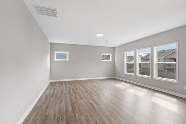 empty room featuring visible vents, baseboards, and wood finished floors