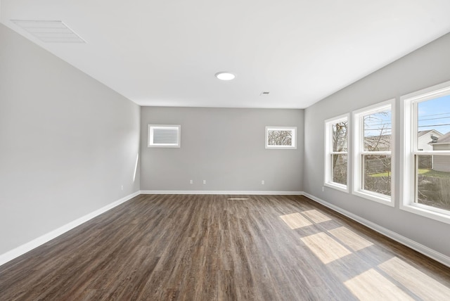 empty room with visible vents, baseboards, and dark wood-style flooring