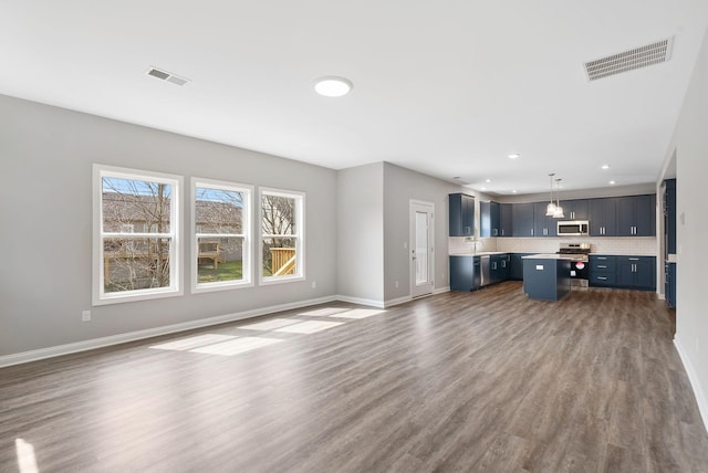 unfurnished living room with a sink, visible vents, baseboards, and dark wood finished floors