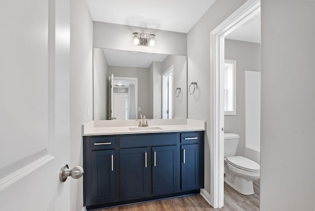 bathroom featuring vanity, wood finished floors, walk in shower, toilet, and a bathtub