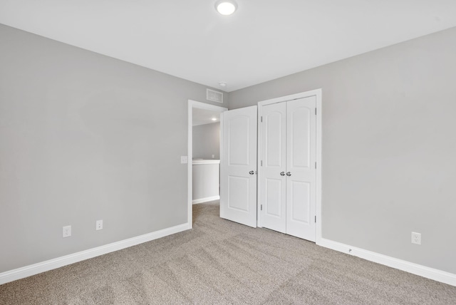 unfurnished bedroom featuring a closet, visible vents, baseboards, and carpet floors