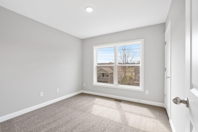 spare room featuring carpet flooring, visible vents, and baseboards