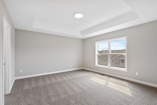 spare room featuring a raised ceiling, baseboards, and carpet floors