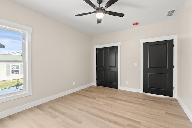 unfurnished bedroom featuring multiple windows, light hardwood / wood-style floors, and ceiling fan