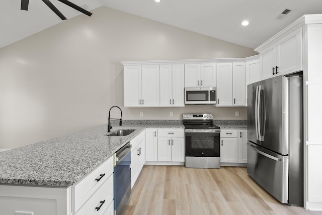 kitchen with lofted ceiling, sink, stainless steel appliances, and white cabinets