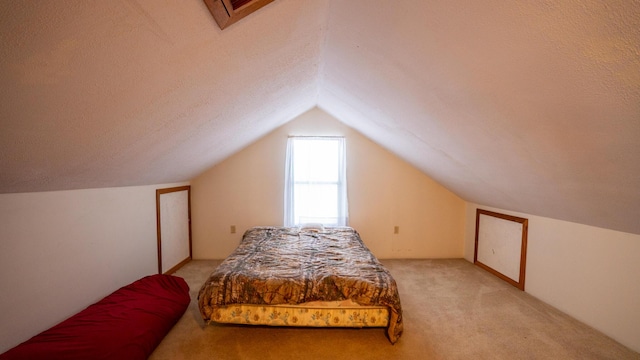 bedroom with a textured ceiling, light carpet, and vaulted ceiling