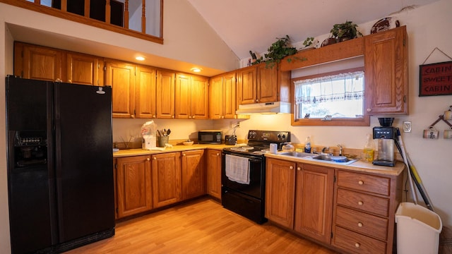 kitchen featuring sink, black appliances, light wood-type flooring, and high vaulted ceiling