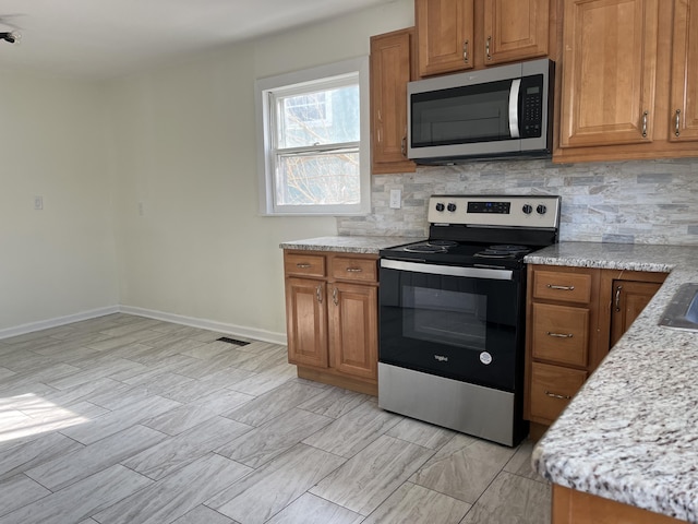 kitchen with light stone counters, stainless steel appliances, and decorative backsplash