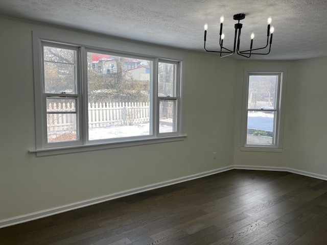 unfurnished dining area featuring dark hardwood / wood-style floors, a textured ceiling, and a notable chandelier