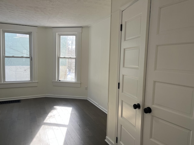 spare room featuring dark hardwood / wood-style flooring and a textured ceiling