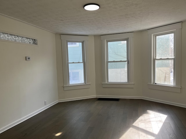 spare room with a textured ceiling and dark hardwood / wood-style flooring