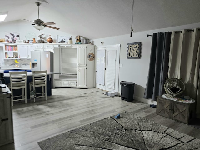 interior space featuring ceiling fan, lofted ceiling, and light wood-type flooring