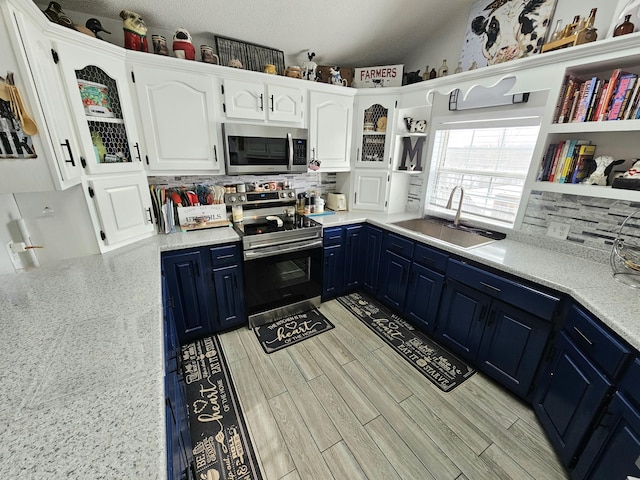 kitchen featuring sink, appliances with stainless steel finishes, white cabinets, blue cabinets, and light wood-type flooring