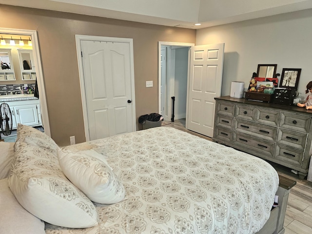 bedroom featuring ensuite bath and light hardwood / wood-style floors