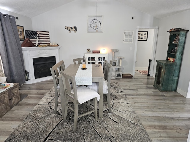 dining space featuring vaulted ceiling, a chandelier, hardwood / wood-style floors, and a textured ceiling