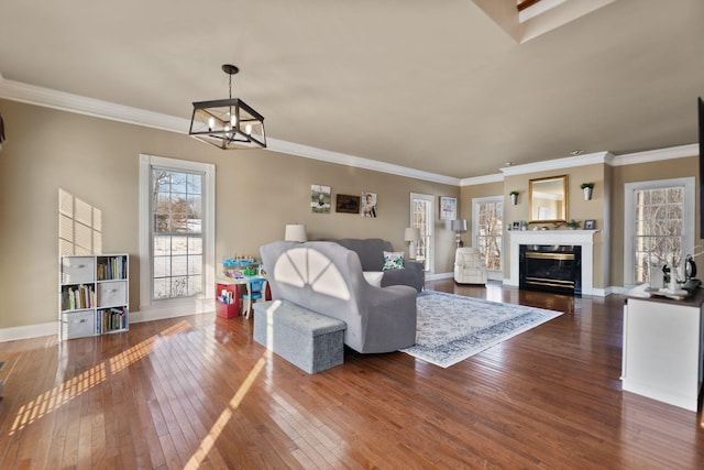 living room with dark hardwood / wood-style flooring, crown molding, a fireplace, and an inviting chandelier