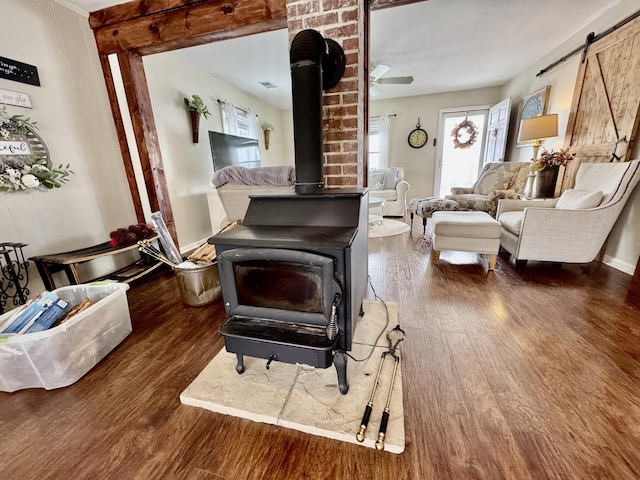 living room with dark wood-type flooring, a barn door, and a wood stove